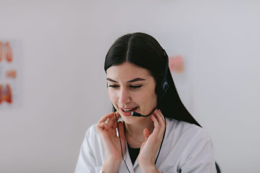 Front portrait view of adorable female young medical operator working in hospital in emergency service. Girl in medical coat talking and connecting with injured and helping them Concept of healthcare and medicine